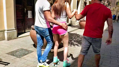 Brunette roller skate babe in tight pink shorts walks with two guys outdoors
