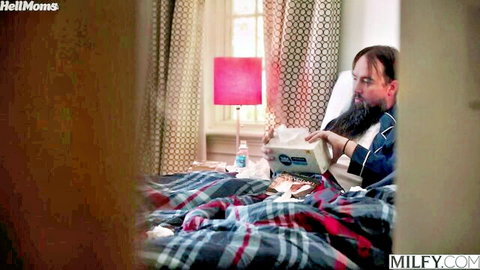 Bearded sick man in bed holding tissues surrounded by MILFY watermarks waiting for milf fuck