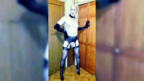 Bald sissy crossdresser exposed in black gloves, harness, stockings, and heels