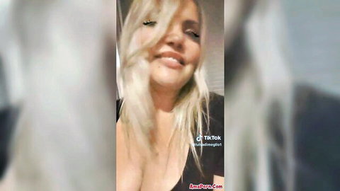 Smiling blonde in low-cut black top showing deep cleavage