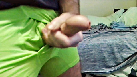Amateur guy standing and stroking his uncut cock in green shorts