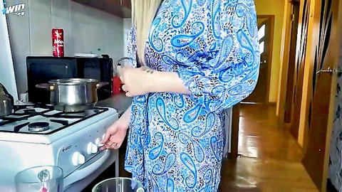 Blonde MILF with huge tits exposes big breasts in open robe while cooking in kitchen POV