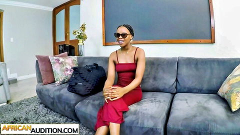 Sexy black babe with perfect booty in red dress, smiling on couch