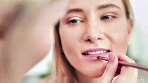 Blonde Ivi Rein applying lipstick sensually close-up