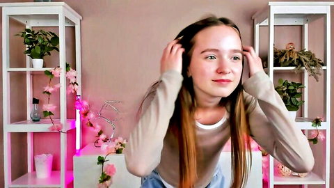 Reagan Prigg smiling, touching long brown hair in sweater on cam