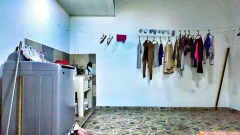 Empty laundry room with colorful clothes hanging on line near washing machine