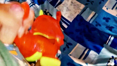 Hand holding red dragon inflatable toy in fetish fun scene