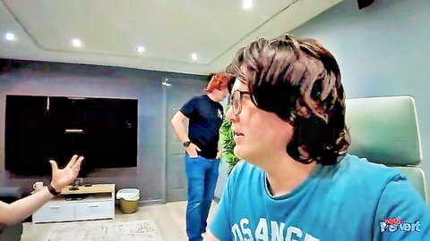 Two men gesturing in casual living room scene from Double Cock Whore adult video