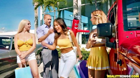 Xander Corvus with busty blondes and Latina in sexy outfits at car dealership