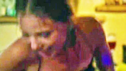 Topless brunette with medium tits leaning forward in kitchen showing bare breasts