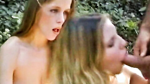 Two nude German babes sharing a cock with blowjobs in the woods