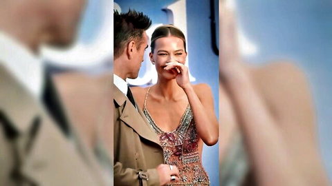Blonde babe in sparkly low-cut dress laughing with handsome man showing deep cleavage on red carpet