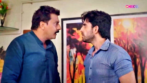 Two clothed Indian men in blue kurtas confront each other intensely in a living room with Chiku watermark.