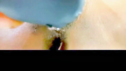 Closeup of shaved pussy with black vibrator inserted squirting blue fluid
