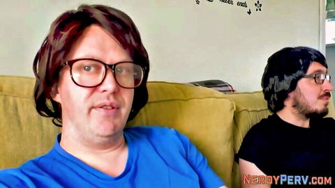 Nerdy couple in glasses and wigs sitting clothed on yellow couch