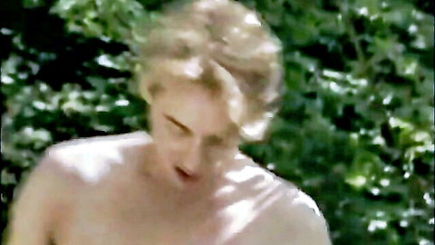 Sensual topless blonde woman pouting outdoors in green forest foliage