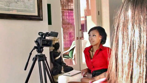 Sexy Asian woman in tight red blouse interviewed by long-haired blonde babe on camera