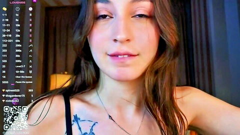 Brunette camgirl with tattoo smiling seductively on Chaturbate live stream