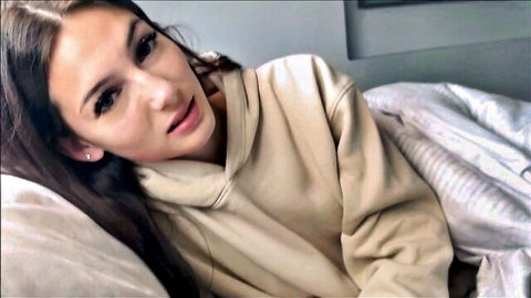 Sophie Tyler in beige hoodie lying in bed, teasing smile for step sis sick day fantasy