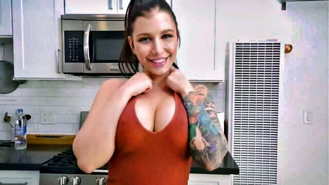 Busty tattooed MILF in tight red dress, smiling seductively