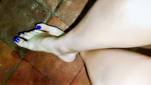 Close-up of pretty female feet with blue toenails on tiled floor