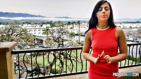Whitney Wright in red dress posing seductively on balcony