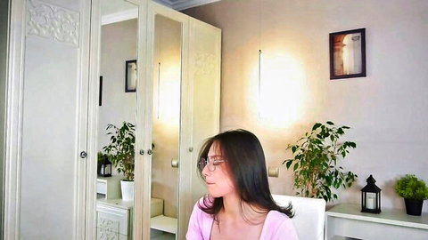 Playful Asian teen with big tits and glasses teases deep cleavage in pink top on webcam