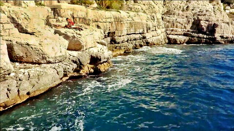 Agathe de La Boulaye in red outfit on rocky seaside cliffs, solo tease