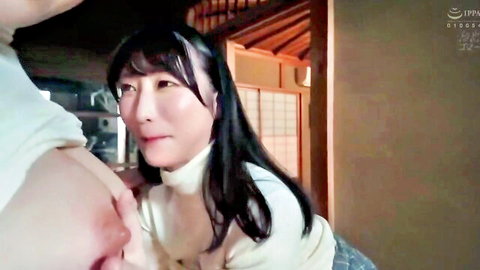 Japanese woman in turtleneck sweater with hand squeezing her big breasts