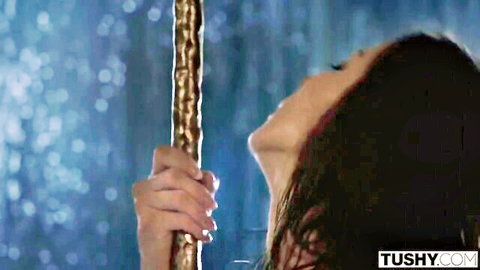 Kendra Lust gripping gold pole seductively with wet hair