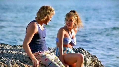 Fabiana Udenio in sexy blue bikini with stud on sunny beach rocks, Hardbodies 2 (1986)