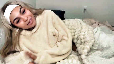 Esteemae1 blonde camgirl smiling in fluffy white sweater on bed