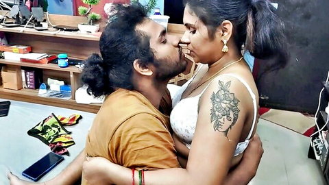 Passionate Asian couple kissing intimately, woman in white bra with arm tattoo