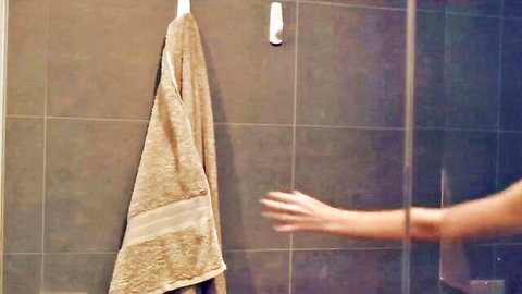 Nude woman reaching hand for towel in steamy shower bathroom