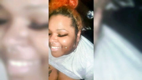 Smiling ebony woman with orange afro hair, lip piercing, close-up in white tee