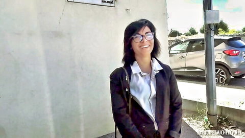 Smiling Asian woman with glasses flashing deep cleavage in open blouse outdoors