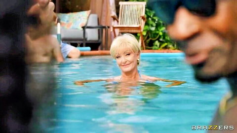 Smiling blonde GILF wet in pool with muscular black stud and friend teasing her tits