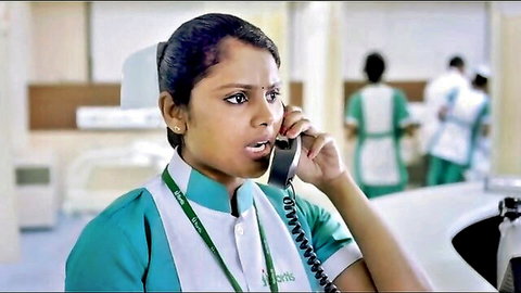 Indian nurse in green uniform on surprised phone call