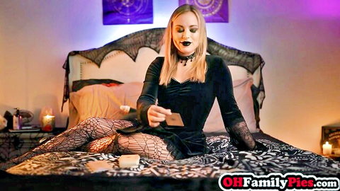 Blonde goth stepsister in black dress and fishnet stockings casting spell with tarot cards