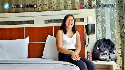 18-year-old Latina student smiling on bed in white tank top for first porn casting