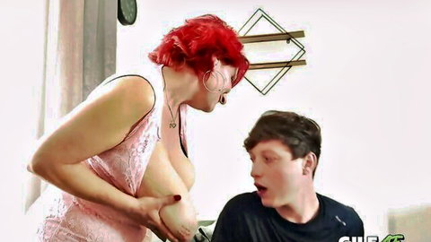 Redhead GILF with massive tits grabs her breast shoving it toward shocked young guy's open mouth