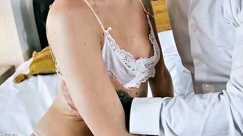 Jazmin Luv in sheer white lace lingerie, embraced intimately by partner on bed