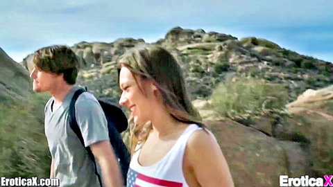 Romantic young couple hiking outdoors, smiling intimately in EroticaX first-time love scene
