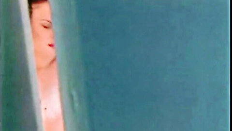 Seductive redhead teen peeking topless from behind door, bare perky tits visible