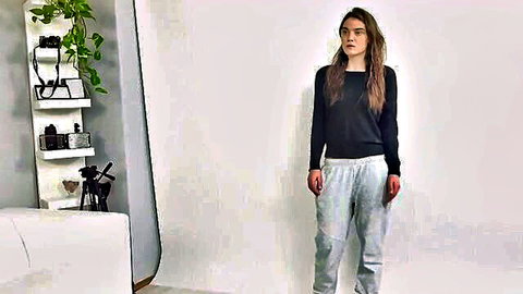 Brunette model posing clothed in black sweater and gray sweatpants in studio casting setup