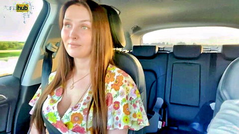 Young stepmom in low-cut floral dress smiling in car after quarrel