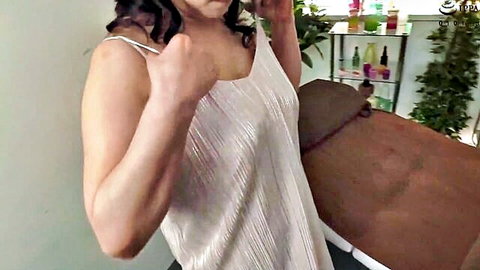Mature Asian woman in low-cut shimmering slip dress posing seductively