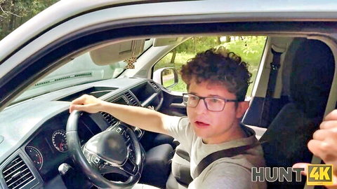 Young curly-haired guy with glasses making O-face while gripping steering wheel in car POV