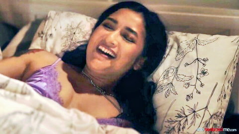 Aiden Starr in purple lingerie, laughing seductively on bed