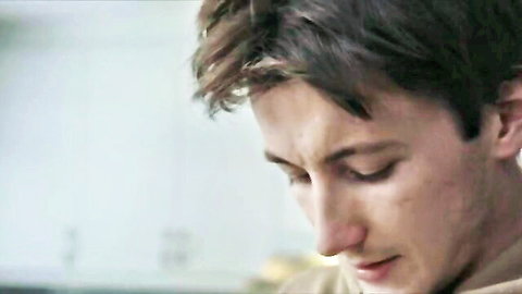 Handsome brown-haired teen boy gazing down intently with parted lips in close-up